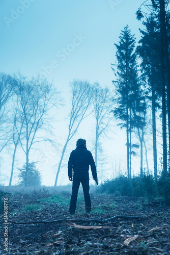 Man in black jacket with gun in foggy winter forest. © ysbrandcosijn