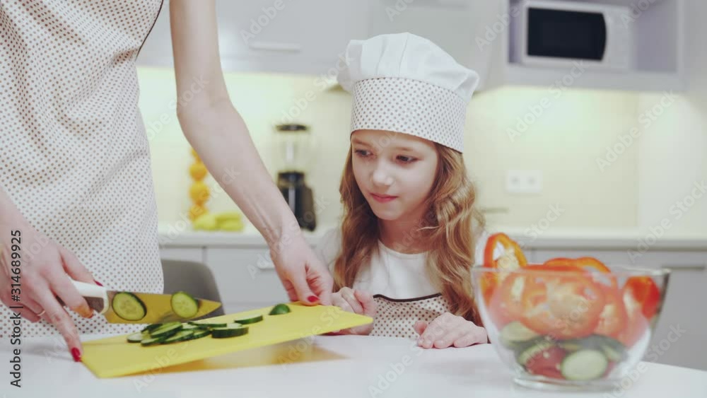 Pretty child watching how her mother cooking fresh salad Pretty child watching how her mother cooking fresh salad