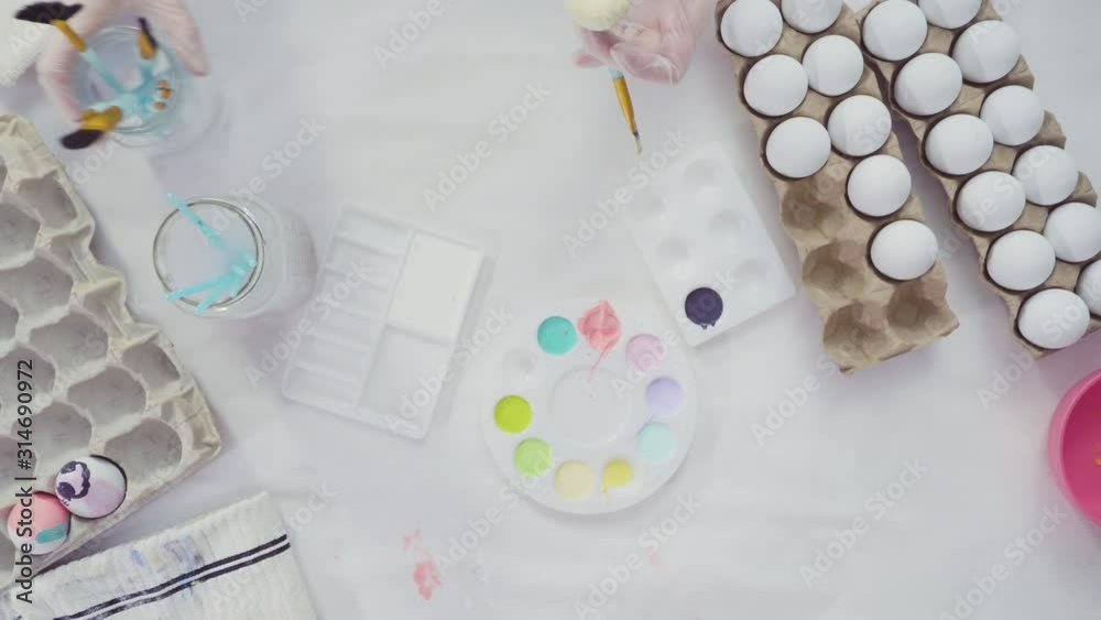 Flat lay. Little girl painting craft Easter eggs with acrylic paint.