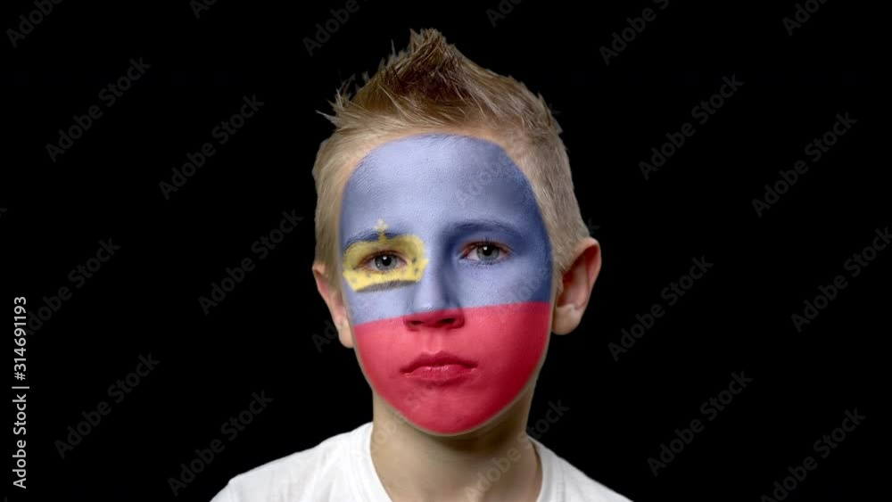 Sad fan of the football team of Liechtenstein. A child with a face painted in national colors. Unhappy boy with sad eyes. Fiasco of your favorite team. Disappointment. Sadness. Experience. Failure. Sad fan of the football team of Liechtenstein. A child with a face painted in national colors. Unhappy boy with sad eyes. Fiasco of your favorite team. Disappointment. Sadness. Experience. Failure.