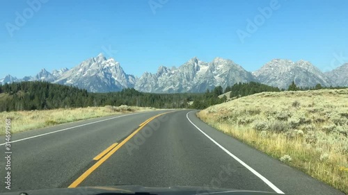 Front view from a car with mountains and forest approaching on a clear sunny day. Grand Teton, Wyoming, United states.