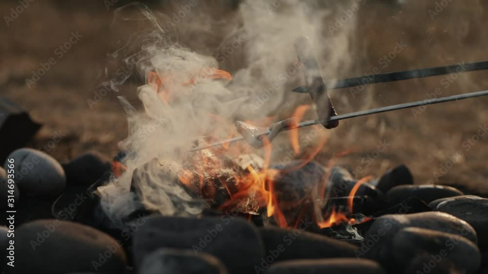Close-up of bacon and sausage on skewers fried on a bonfire during a picnic in nature Close-up of bacon and sausage on skewers fried on a bonfire during a picnic in nature