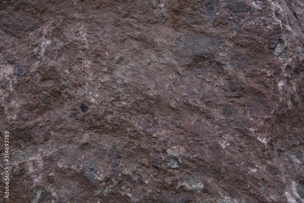The texture of natural mountain stone. Burgundy brown color stone structure. Background, pattern, banner.
