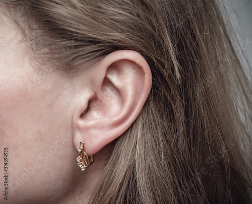 Female ear with a golden earring