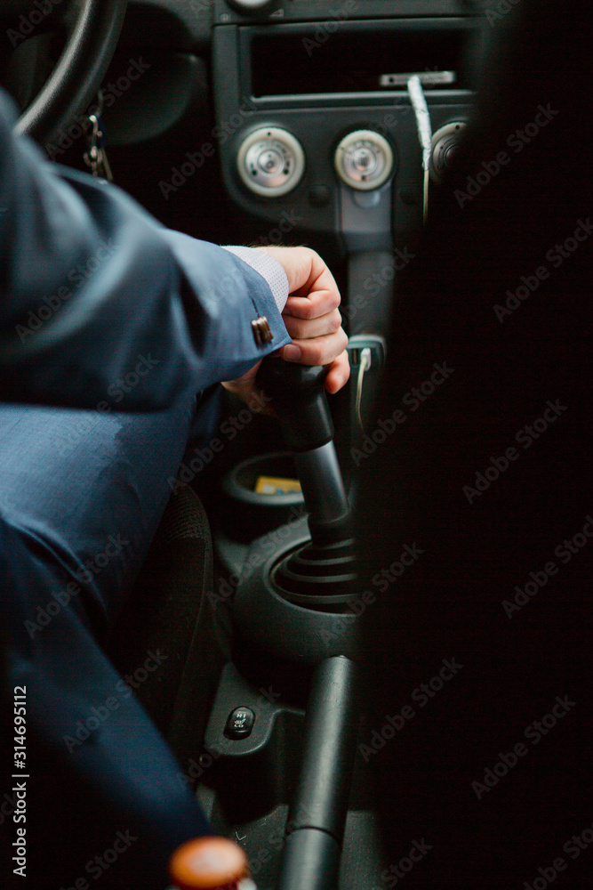 A man in a business suit holds his hand on the gear knob, a machine with a manual gearbox A man in a business suit holds his hand on the gear knob, a machine with a manual gearbox