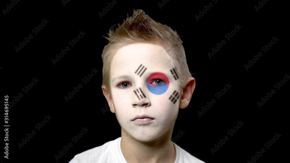 Sad fan of the football team of South Korea. A child with a face painted in national colors. Unhappy boy with sad eyes. Fiasco of your favorite team. Disappointment. Sadness. Experience. Failure. 