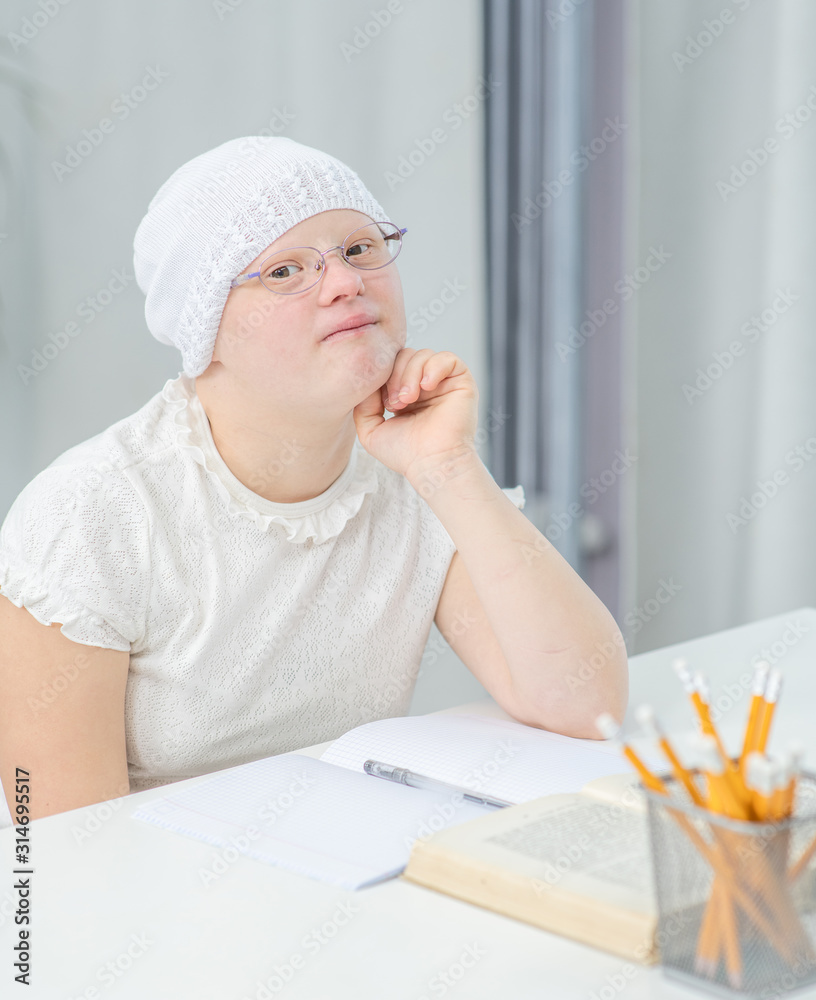 Portrait of a smart girl with Down Syndrome with books at home