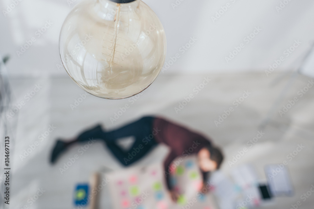 selective focus of light bulb near scrum master lying on floor selective focus of light bulb near scrum master lying on floor