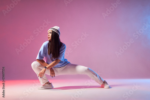 Charming lady posing on colourful smoke wall, squatting, looking away, ready to start dancing, waiting for energetic music, modern life style dance concept