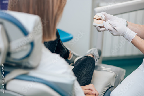 cropped unrecognizable dentist and patient in dental office, doctor show prosthesis to patient. Health and medicine concept