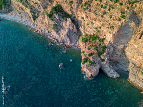 Aerial view of a steep cliff and a motor boat. Jagged coast on the Adriatic Sea. Cliffs overlooking the transparent sea. Wild nature and Mediterranean maquis © Naeblys