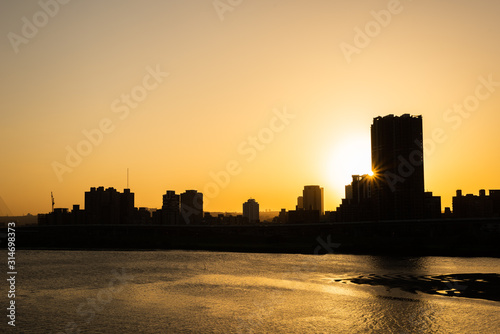 silhouette of buildings with river at sunset