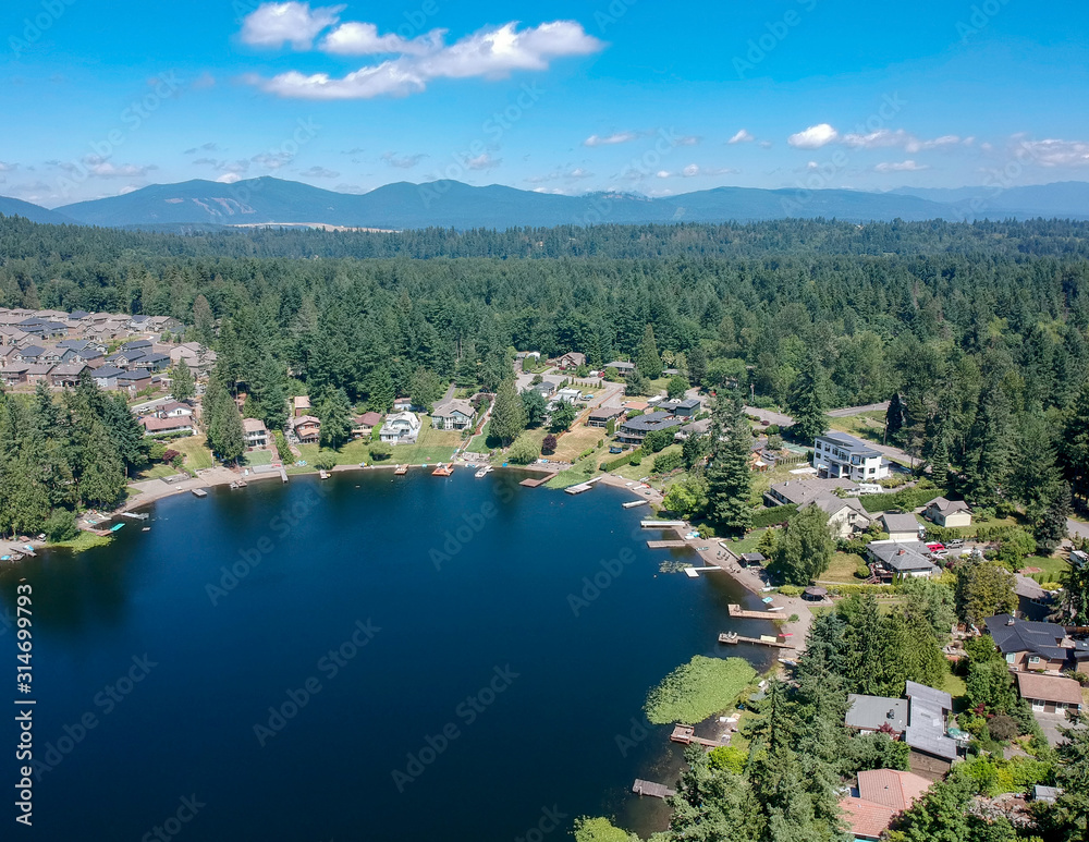 Tranquil Shady Lake on a bright clear day in summertime with trees reflecting in the water a blue sky and white clouds with lily pads dockside in Renton King County Washington State