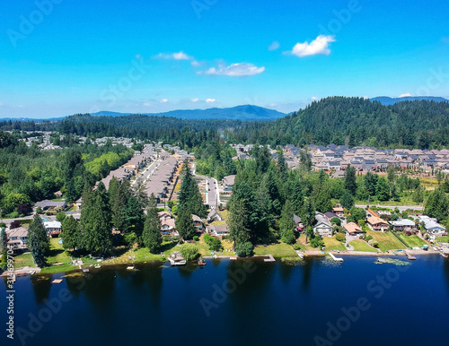 Tranquil Shady Lake on a bright clear day in summertime with trees reflecting in the water a blue sky and white clouds with lily pads dockside in Renton King County Washington State