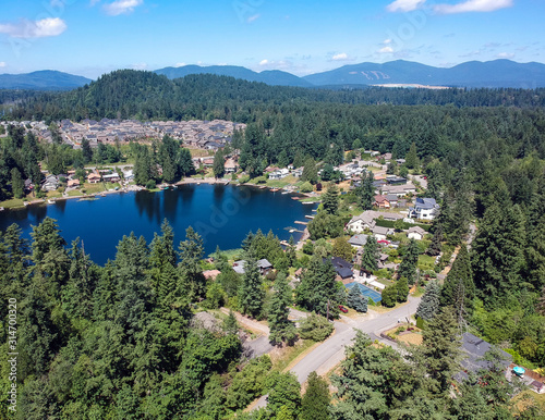 Tranquil Shady Lake on a bright clear day in summertime with trees reflecting in the water a blue sky and white clouds with lily pads dockside in Renton King County Washington State
