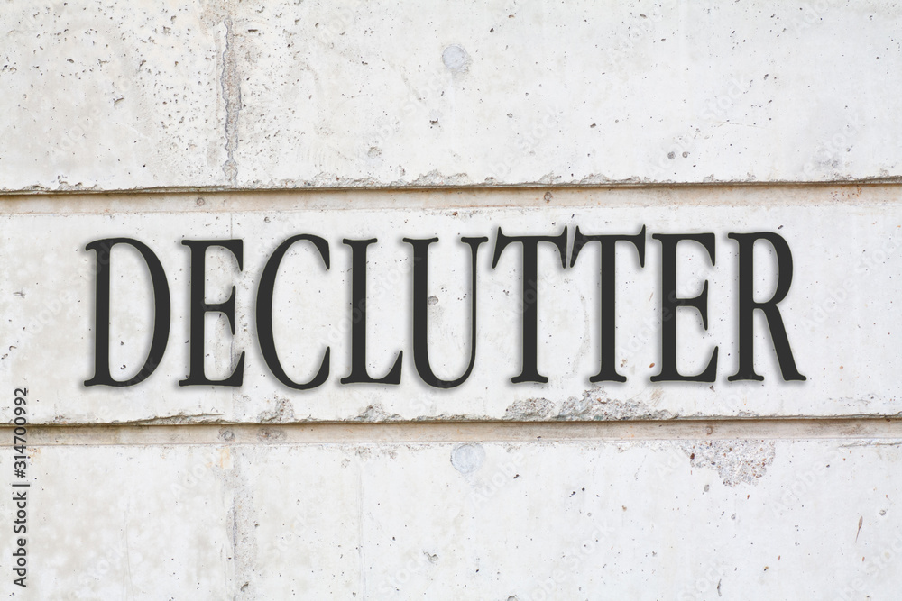 written DECLUTTER word on concrete wall background