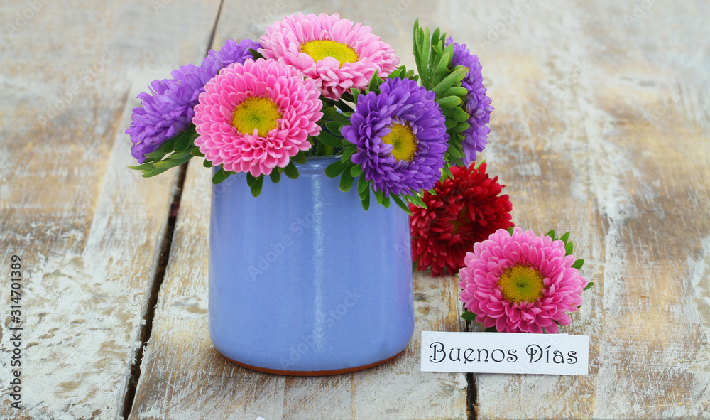 Buenos dias (good morning in Spanish) card with colorful daisies in blue vase on rustic wooden surface