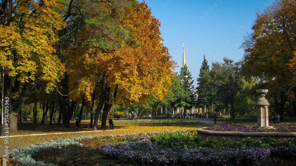 autumn park, yellow leaves, flower bed with flowers, blue sky, church, Dnipro city, Ukraine