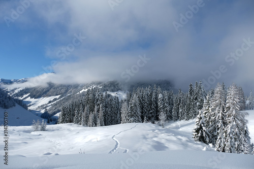 Beautiful panorama of snow covered Kitzbuehleler Horn, Austrian alps mountain peak. Low clouds hang around the mountain ranges and over the valley. Glittering shiny deep fresh powder snow foreground.