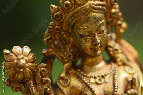 Figure of a female Buddhist deity  Green Tara  sitting on a lawn 