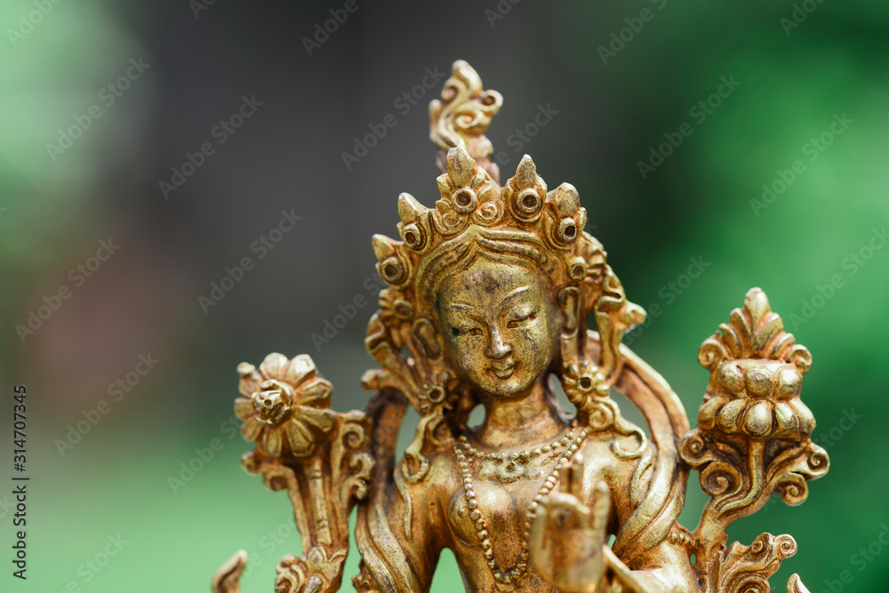Figure of a female Buddhist deity (Green Tara) sitting on a lawn 
