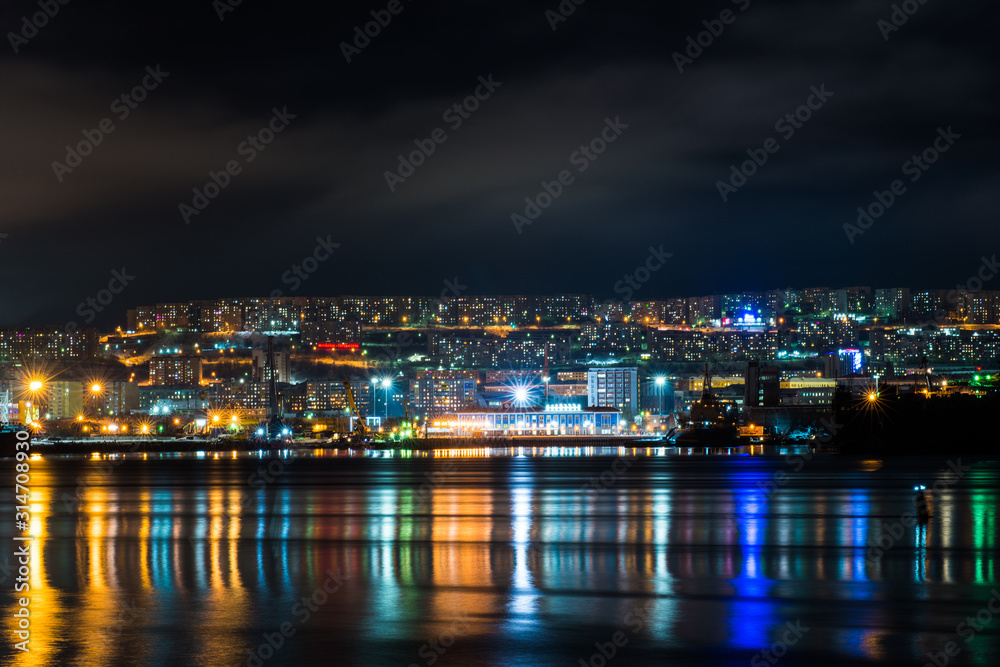 night Murmansk, city lights reflected in the Bay and the ships standing in the port