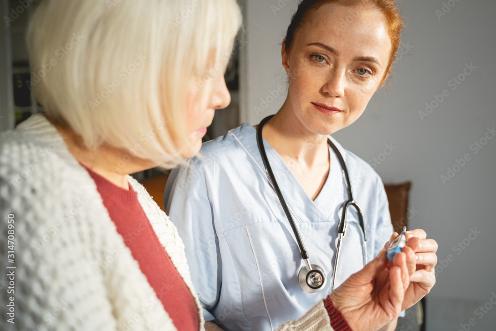 Cute medical worker checking temperature of her patient Cute medical worker checking temperature of her patient