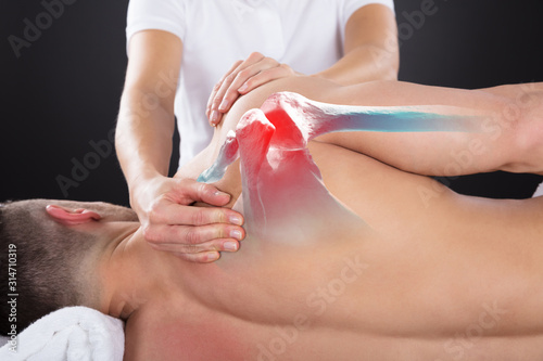 Physiotherapist Doing Treatment On Man's Shoulder