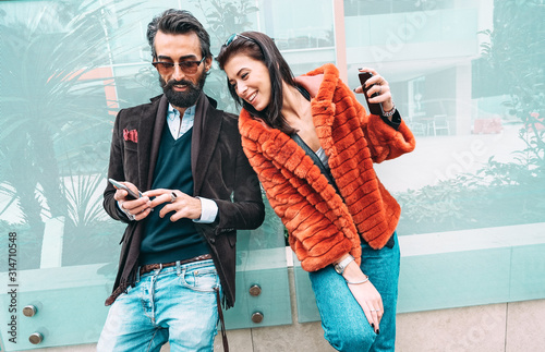 Modern hipster couple having fun using mobile smart phone outside - Social interaction concept with friends sharing digital content on social media networks - Millenial generation dating online