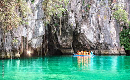 Cave entrance of Puerto Princesa subterranean underground river with longtail boat - Wanderlust travel concept at Palawan exclusive Philippine destination - Vivid filter with bulb torch light sunflare photo
