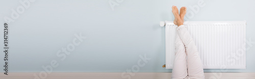 Woman Warming Up Her Feet On White Radiator