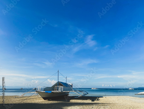 Beautiful white ship close-up on background of blue calm sea and sky with clouds. Boats on the horizon.Cozy sandy beach photo