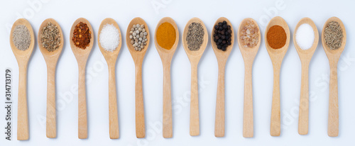 Various spices in wooden spoons, isolated background