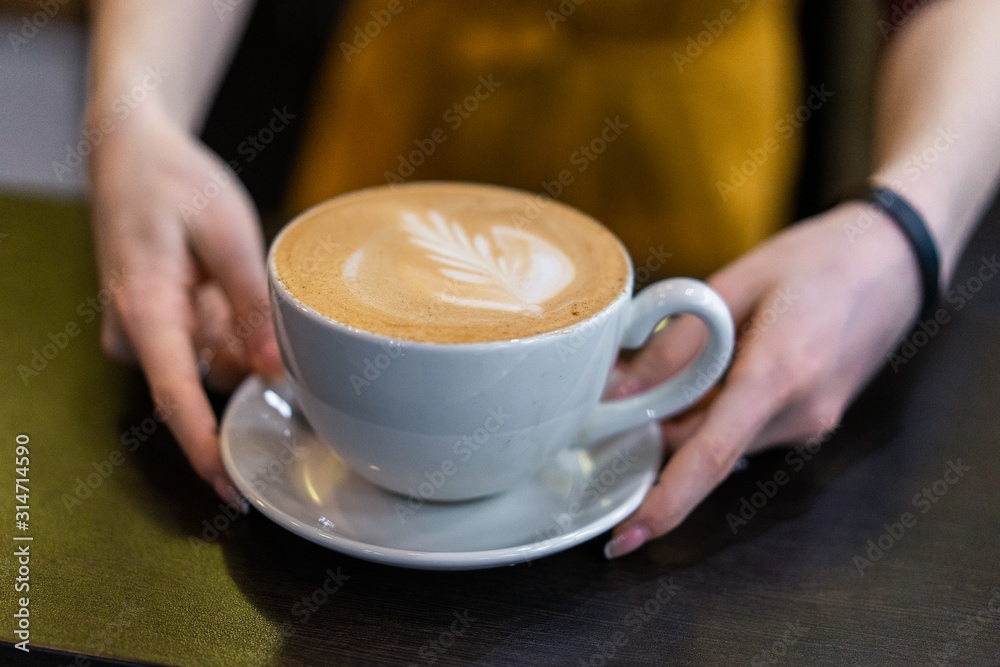 coffee in the hands of a girl on a brown background