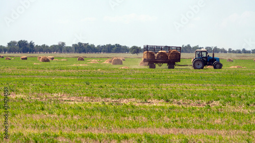 Tractor loading hay bales on truck agricultural works