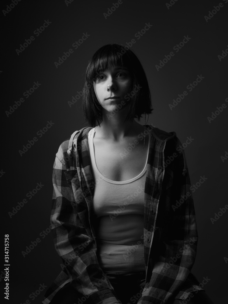 Young woman in shirt sitting in studio. Black and white