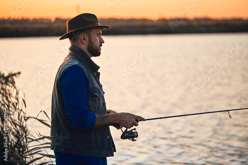 Caucasian man fishing near lake. Sunset. Background lake.