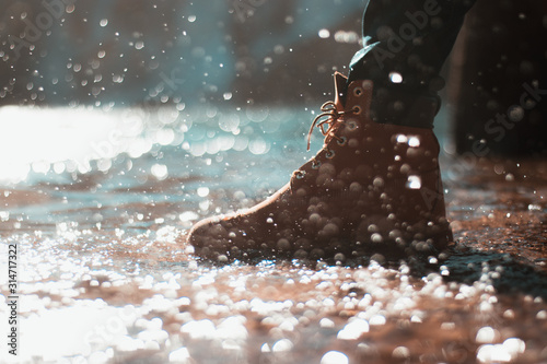 River water splashing on an orange man's boot. Frozen moment , action shot. Blue waterfall in the distance.