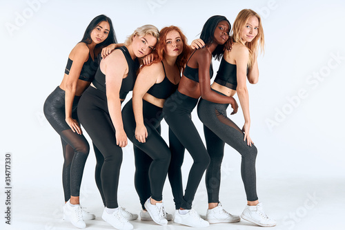 Portrait of various size and appearances girls, stand together, leaned on each other