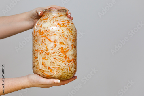 Isolated sauerkraut. jar of sauerkraut in women's hands