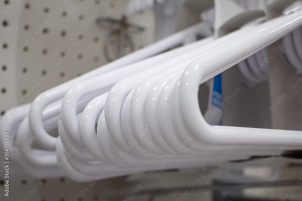 A closeup view of several white hangers on display at a local department store. A closeup view of several white hangers on display at a local department store.