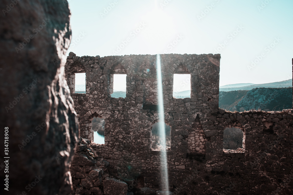 Ruined wall of an ancient fortress in bosnia and herzegovina , pocitelj. Ruins with window holes, sun flare across the image Ruined wall of an ancient fortress in bosnia and herzegovina , pocitelj. Ruins with window holes, sun flare across the image