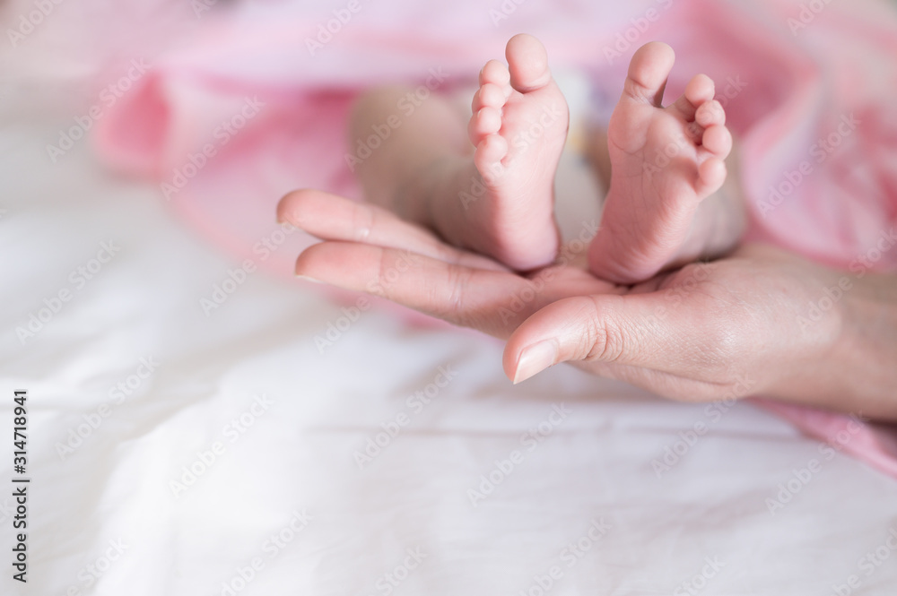 Baby foots on mother hand.Newborn baby feet and relax action with pink blanket.Happy time family concept.