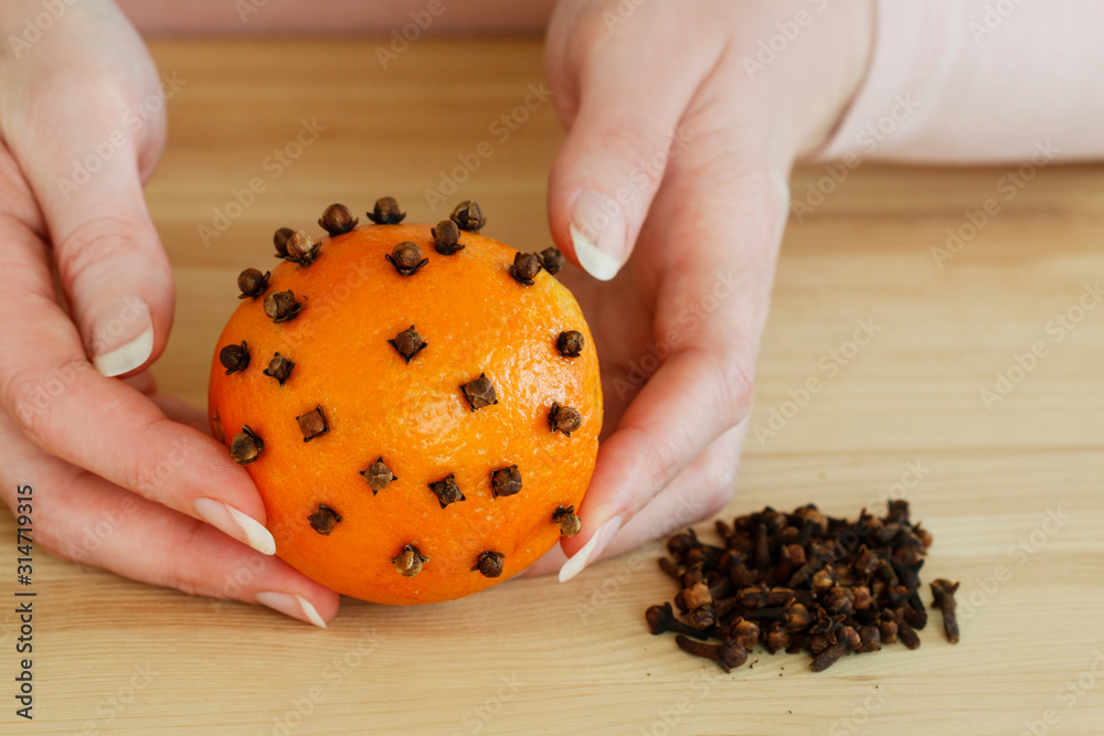Woman shows how to make orange pomander ball with candle Woman shows how to make orange pomander ball with candle