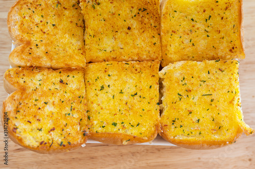 Fotografija Row of delicious homemade garlic bread on wooden background