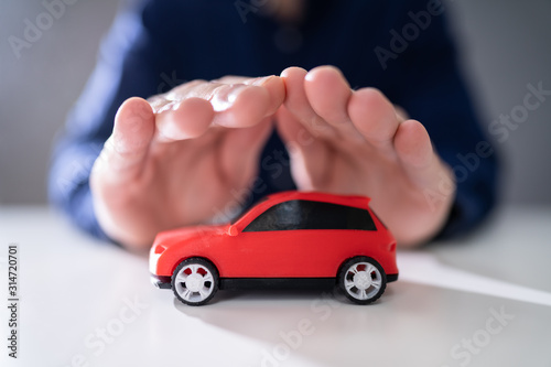 Businessman's Hand Protecting Red Toy Car