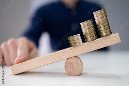 Businessperson Balancing Increasing Stacked Coins With Finger photo