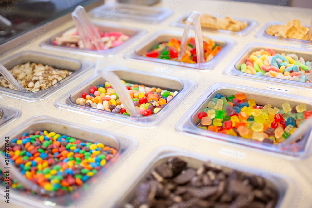 A view of several containers full of popular ice cream toppings on display  at a local ice cream shop. Stock Photo | Adobe Stock