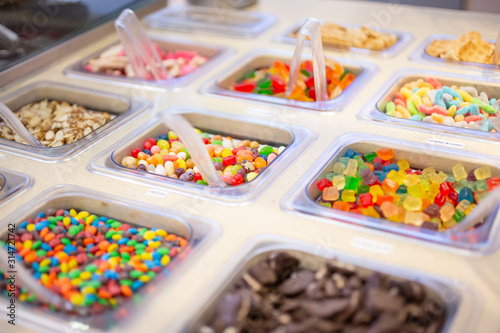 A view of several containers full of popular ice cream toppings on display at a local ice cream shop. photo