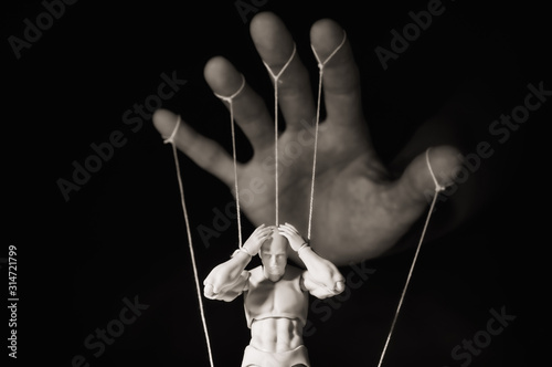 Concept of control. Marionette in human hand. Black and white image